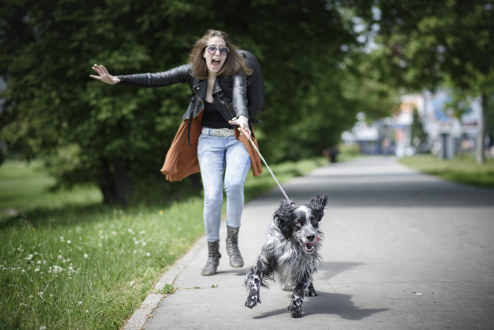 Young Woman Walking Her Dog on a Street, Having Troubles